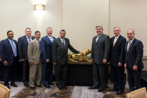 The IAS board presents a gold tiger to Ramani upon his retirement. As the national animal of India, the tiger symbolizes power and appears on the currency notes disseminated by the Reserve bank of India. Pictured (left-right): IAS Board member Devang Jhaveri, IAS Board member James, ICC Board member Stuart Tom, former IAS Board Chair James Toscas, Chuck Ramani, IAS Board Chair Rocco Davis, Dominic Sims, and IAS Board member Shahriar Amiri