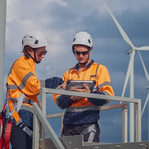one man aond one woman with laptop out checking wind turbines