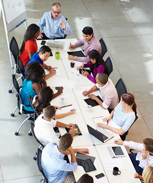 overhead view of people in an office sitting at a large conference table deep in discussion