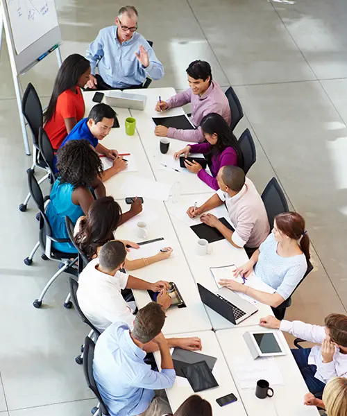overhead view of people in an office sitting at a large conference table deep in discussion