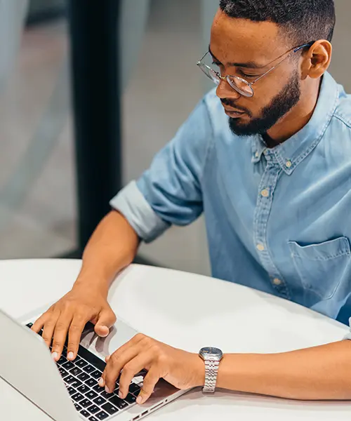 man sitting at desk typing on a laptop