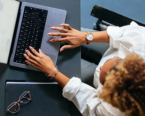birds eye view of woman working on laptop at desk, keyboard is in focus