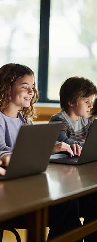 children in a classroom using laptop computers