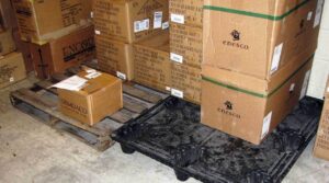 A wood pallet (left) sits next to a “nestable” plastic pallet. Idle nestable pallets can be stacked on top of one another to save space.