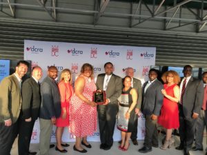 DCRA Director Melinda Bolling (fifth from left) and City Administrator Rashad Young (seventh from right) hold the plaque presented by IAS. DCRA Deputy Director Lori Parris (sixth from right) and Chief Building Official Lynn Underwood (fifth from right) were also in attendance.