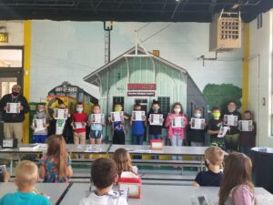 Code Council Board Director Ron Hampton (far left) visited Carter Christian Academy to discuss Building Safety Month with the students (kindergarten through fourth grade) and interact with them through activity and coloring books.