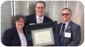 Meghan Housewright with the Coalition for Current Safety Codes and International Code Council Board of Directors President Alex Olszowy, III (right), with the Lexington Fayette County Government in Lexington, Ky., present a Certificate of Appreciation to Kyle Pitsor of the National Electrical Manufacturers Association during the annual Building Safety Month reception at the ICC office in Washington, D.C.